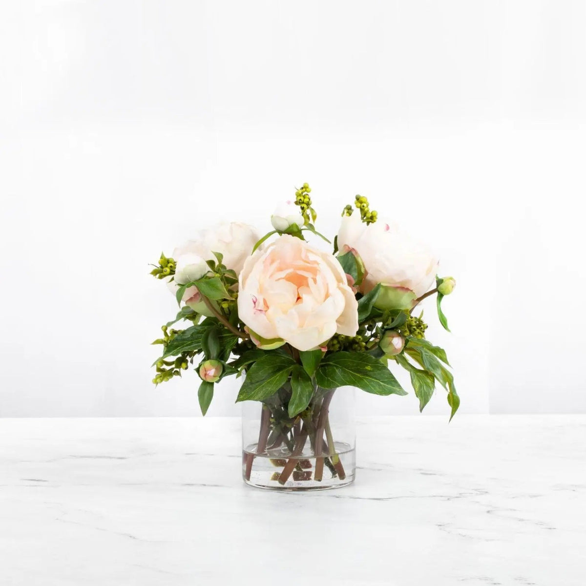Composition de pivoines artificielles dans un vase en verre