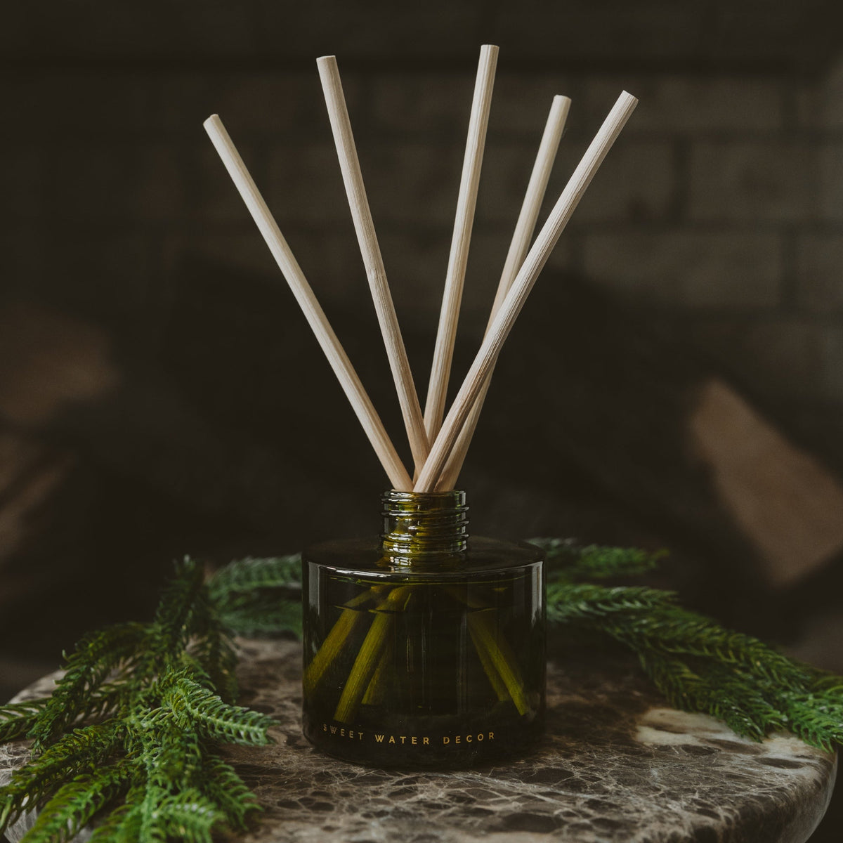 Diffuseur à bâtonnets dans un bocal en verre teinté olive, ambiance chaleureuse et douillette