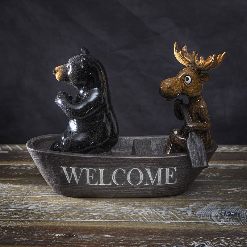 Whimsical black bear and moose canoeing figurine crafted from resin, a rustic woodland accent for cabin and lodge home decor.